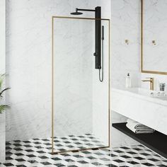 a bathroom with black and white tile flooring, gold trimming on the shower