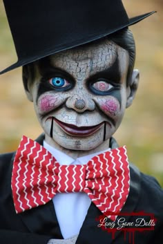 a close up of a person wearing a top hat and bow tie with makeup on