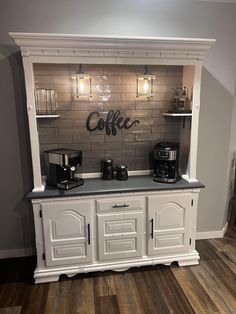 a coffee bar with white cabinets and black counter tops