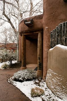 an adobe building with snow on the ground