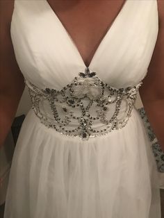 the back of a woman's white dress with beading and pearls on it