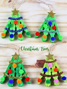 four christmas trees made out of construction paper and pom poms hanging from strings