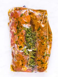 a bag filled with meat and vegetables sitting on top of a white countertop next to a knife