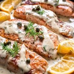 grilled salmon with lemons and capers on a white plate topped with cream sauce