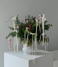 a white vase filled with greenery and candy canes on top of a table