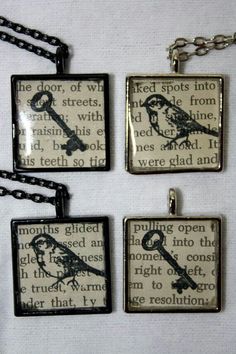 four square pendants with keys and words on them are hanging from chain necklaces