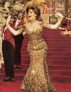 a woman in a gold dress is standing on the red carpet with her arms outstretched