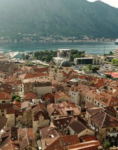 an aerial view of a city with buildings and mountains in the backgrouds