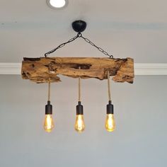 three light bulbs hanging from a wooden beam in a room with gray walls and white trim