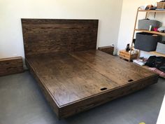 a bed frame made out of wood in a room with shelves and other items on the wall