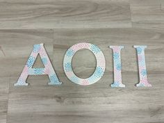 the word aoi spelled with painted letters on a wood floor in pink, blue and white