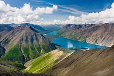 the mountains are covered in green and blue water