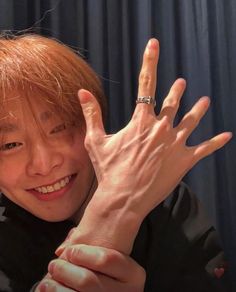 a woman with red hair holding her hand up in front of her face and smiling at the camera