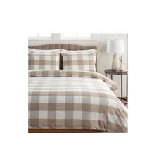 a bed with plaid sheets and pillows on it