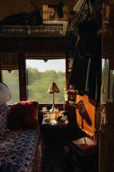 the inside of a vehicle with a bed, table and lamp next to it in front of a window