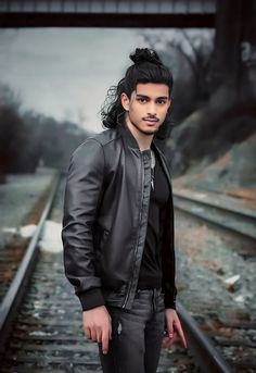 a man standing on train tracks with his hands in his pockets