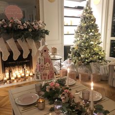 a christmas table setting with candles, plates and other holiday decorations in front of a fireplace