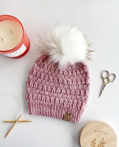 a knitted beanie hat next to a pair of scissors and a jar of thread