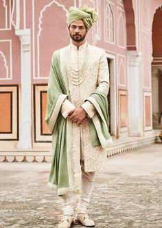 a man in a turban standing on the ground with his arms folded up