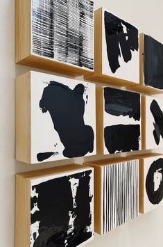 four black and white paintings hanging on the wall next to each other in wooden frames