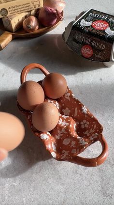 an egg carton with four eggs in it next to some other food on the table