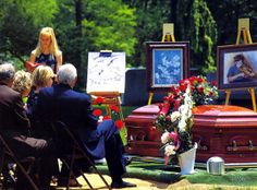 people are sitting in chairs and looking at pictures on easels, with one woman standing