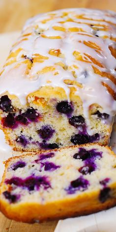 a loaf of blueberry bread with white glaze on top is cut in half