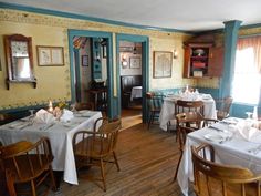 a dining room with tables and chairs covered in white tablecloths set for dinner