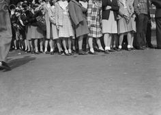 a group of people standing next to each other in front of a crowd on the street