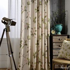 the curtains in this room are made with floral print and have a tripod stand next to it