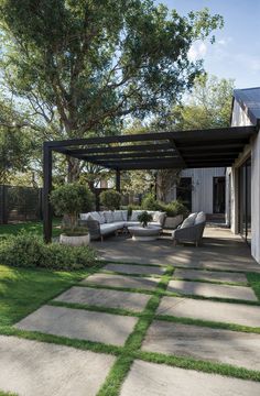 an outdoor living area with couches, tables and grass in front of the house