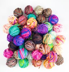 multicolored balls of yarn sitting on top of each other in various sizes and colors