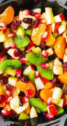 fruit salad with kiwis, oranges, and cranberries in a skillet