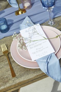 a place setting with pink plates and blue napkins