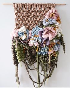 a bunch of flowers that are hanging on a wall next to a piece of string