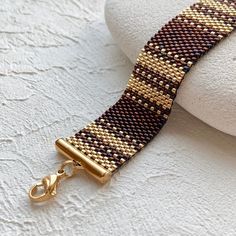 a close up of a gold and brown bracelet on a white surface with a hook