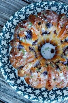 a blue and white plate topped with a bundt cake covered in icing on top of a wooden table