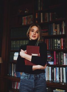 a woman standing in front of a bookshelf with her arms crossed