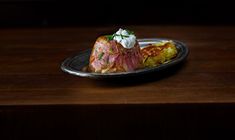 a plate with food on it sitting on a wooden table next to a glass bottle