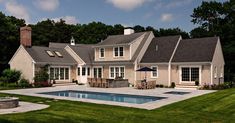 a large house with a pool in the front yard and an outdoor dining area next to it