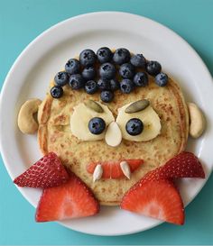 a plate topped with pancakes and fruit on top of each other, face painted to look like a man