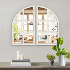 two white arched windows with plants and books on the table