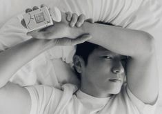 a man laying in bed with his hands on his head and an electronic device above his head