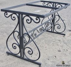 an iron work table with intricate designs on it's sides and bottom, sitting in the middle of a parking lot