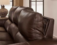 a brown leather couch sitting in front of a table with a lamp on top of it