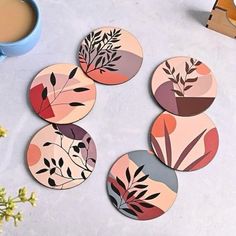 four coasters with different designs on them next to a cup of coffee and flowers