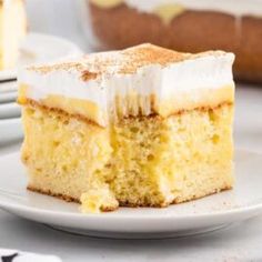 a slice of lemon cake on a plate with the rest of the cake in the background