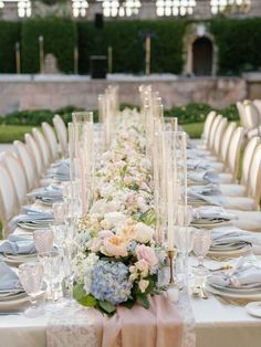 a long table is set with silverware and pink flowers on the centerpieces