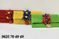 three clutches with bows and beads on them sitting next to each other in front of a white background