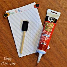 a piece of paper and glue sitting on top of a wooden table next to a notepad